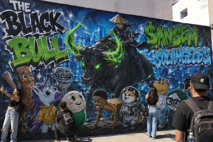 A vibrant mural featuring "THE BLACK BULL" and "$ANSEM SOLANCELESS" graffiti with a masked figure riding a glowing-eyed bull, surrounded by cartoon characters that appear to be meme avatars, while people take photos in front of it—visually capturing the "bullish" crypto enthusiasm referenced in the post.