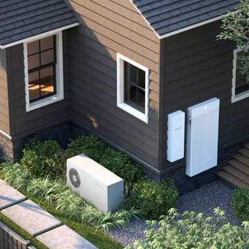 The image shows a house with two white boxes placed outside, one of which appears to be an air conditioning unit or heat pump. The house has a brown roof and is surrounded by bushes and plants. There are also some steps leading up to the front door. The text in the image reads "We have been doing this with Bitcoin miners since 2022." This suggests that the house might be used as a living space for Bitcoin mining operations, possibly as an alternative source of income or investment.