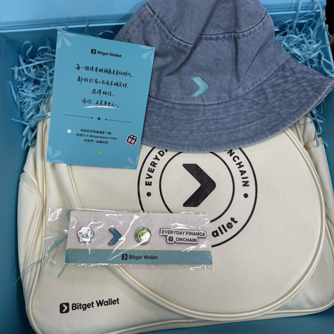 A promotional gift box from "Bitget Wallet" containing a denim bucket hat, a cream canvas bag, and pin badges reading "EVERYDAY FINANCE ONCHAIN" and "Bitget Wallet," accompanied by a blue informational card with Chinese text.