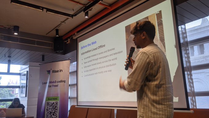A young man with a microphone gives a presentation in front of a projected slide titled 'Before the Web', with a 'Rise in Web3 coding for Free!' banner nearby.