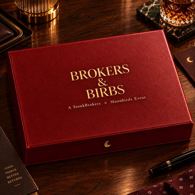 An elegant red velvet box on a wooden desk with gold text reading 'BROKERS & BIRBS - A StonkBrokers x Moonbirds Event'.