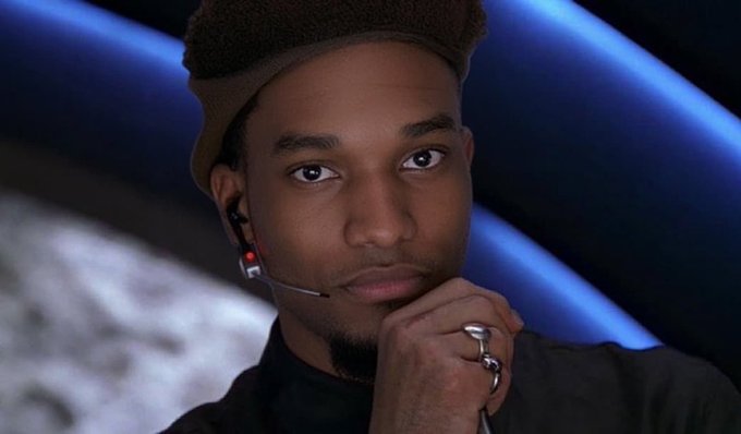 A young man wearing a beige hat and earpiece rests his chin on his hand, with a blue-lit background behind him. The image illustrates the caption's reference to a deceptive crypto promoter orchestrating a rug pull by distributing tokens to shill accounts before abandoning the project.

Note: The caption describes a general scenario but does not identify the individual. Based on the context provided and visible features, this could be content creator Threadguy, mentioned in the post.
