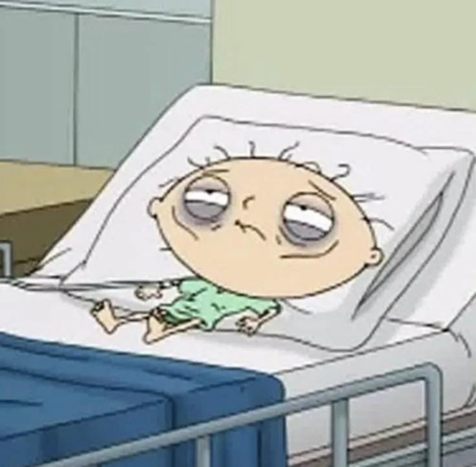 A cartoon image of Stewie Griffin from Family Guy lying in a hospital bed with a bruised, beat-up face and a sinister smirk.