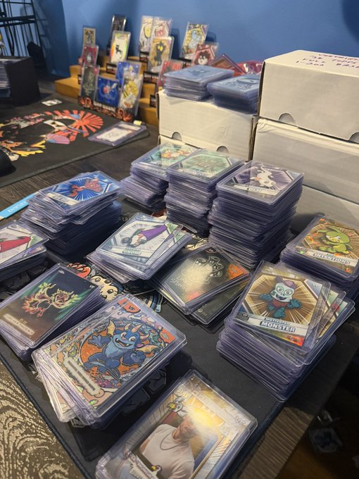 A display table stacked with numerous protective cases of trading cards, including various anime and character-themed decks.