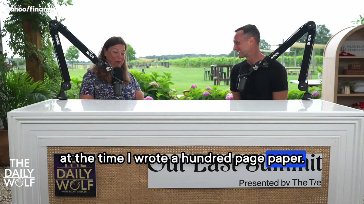 A screenshot from Yahoo Finance's 'The Daily Wolf' podcast featuring two hosts at microphones with the subtitle 'at the time I wrote a hundred page paper. it' and branding 'Out East Summit Presented by The T[e]'.