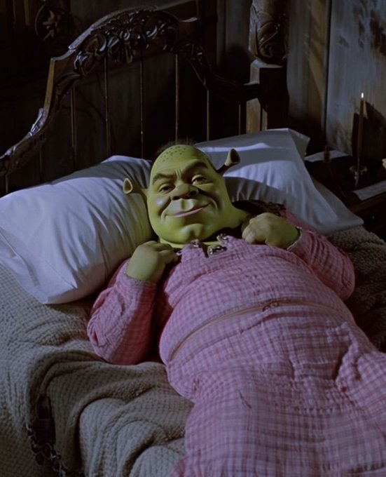 A Shrek mask character lying in a bed wearing pink plaid pajamas, smiling contentedly with hands tucked under the chin.