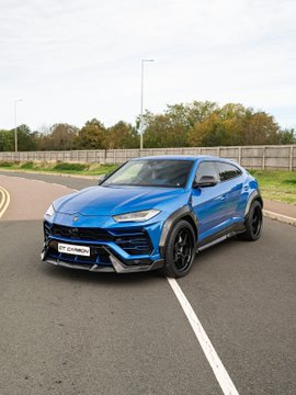 A vibrant blue Lamborghini Urus SUV is parked in an empty lot with its sleek design and black wheels prominently displayed, but the image has no apparent connection to the post's promotion offering $15 in exchange for engagement and a Solana address.