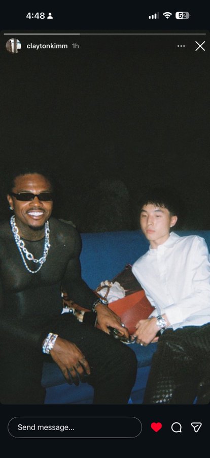 A screenshot of an Instagram story from 'claytonkimm' posted 1 hour ago shows two men sitting together on a blue couch at night, one in a black sheer top with silver chains and sunglasses, the other in a white shirt.