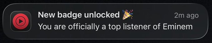 A mobile notification from YouTube Music stating "New badge unlocked 🎉 You are officially a top listener of Eminem" received 2 minutes ago.