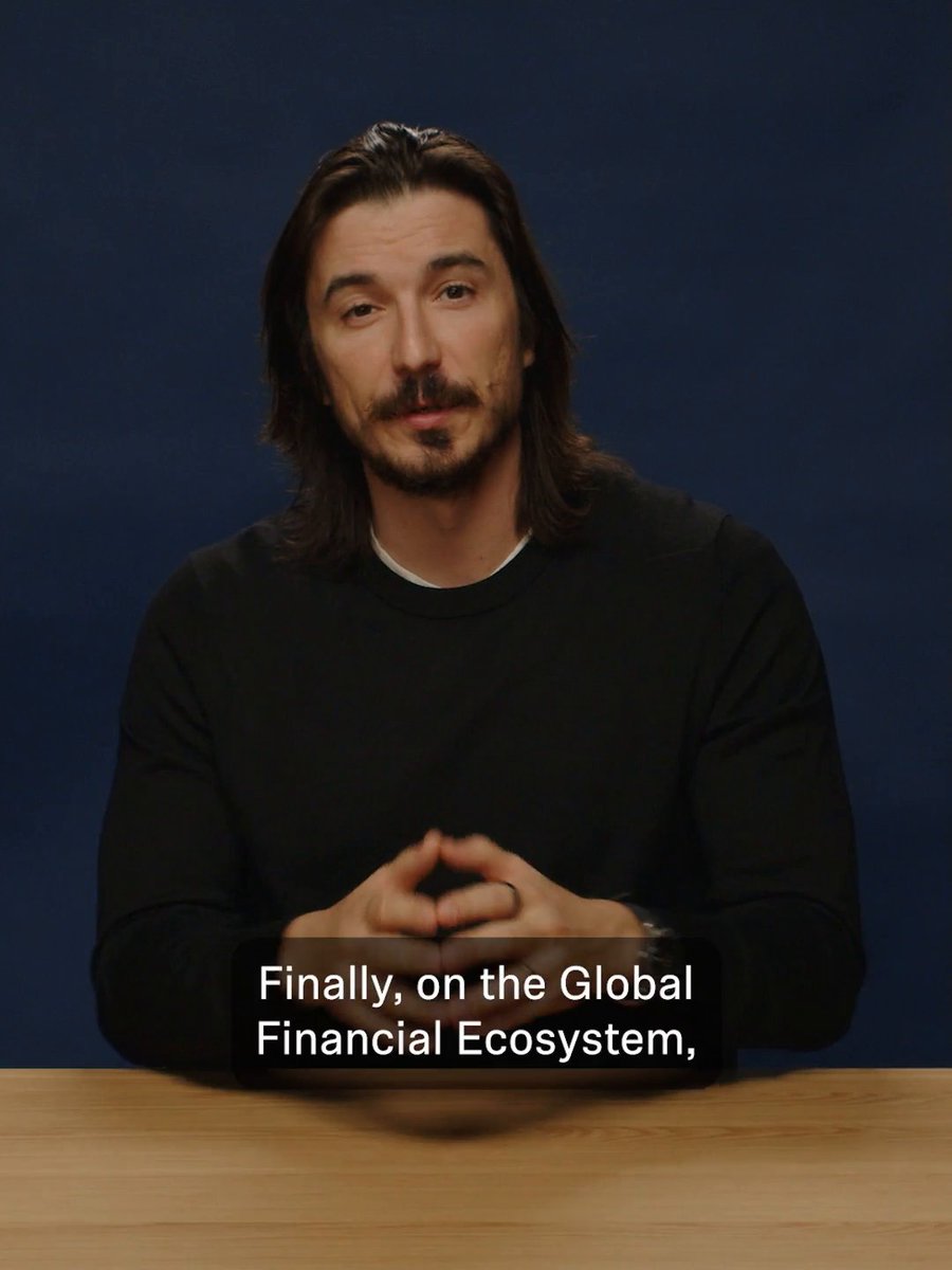 A man with long dark hair and a mustache sits at a table against a dark blue background, with the on-screen text reading, “Finally, on the Global Financial Ecosystem,”. The image appears to accompany a post praising Vlad Tenev and Robinhood App, framing “boner coin” as an emerging financial-ecosystem success story.
