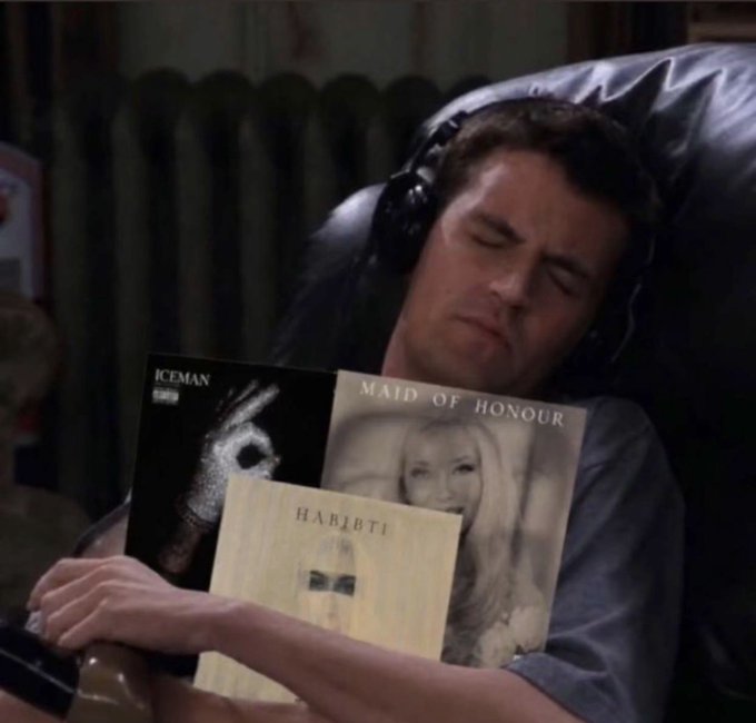 Chandler Bing from the TV show Friends sleeps in a black leather chair while holding vinyl records labeled 'ICEMAN', 'MAID OF HONOUR', and 'HABIBTI'.