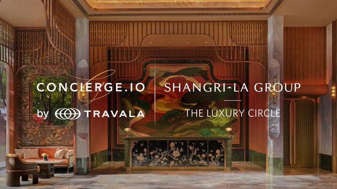 An elegant luxury hotel lobby interior serving as a backdrop for a partnership announcement between 'CONCIERGE.IO by TRAVALA' and 'SHANGRI-LA GROUP - THE LUXURY CIRCLE,' featuring ornate decor and a green marble console table.