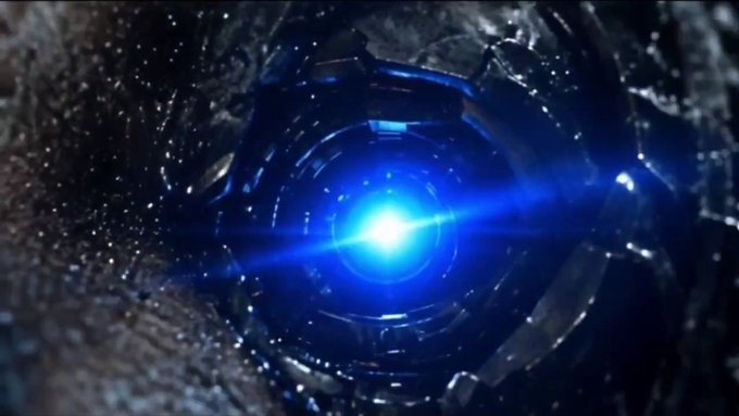 A dramatic visual effect showing a bright blue glowing light or energy burst at the center of what appears to be a dark tunnel or mechanical structure with metallic textures.