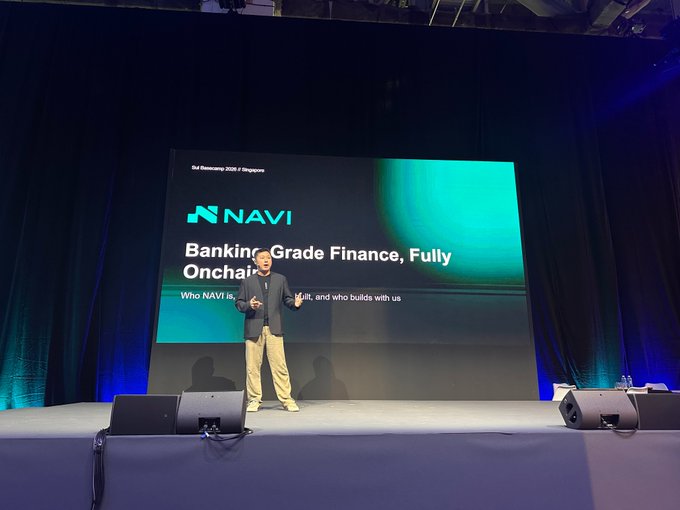 A man giving a presentation on stage at 'DUI Retrecamp 2023 / Singapore' in front of a large screen displaying the 'NAVI' logo and the text 'Banking-Grade Finance, Fully Onchain'.