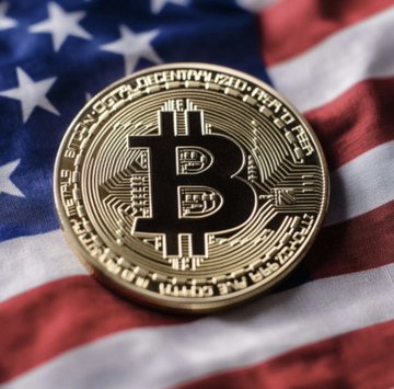 A physical Bitcoin token rests atop an American flag, symbolizing the convergence of cryptocurrency and U.S. policy as the White House signals imminent passage of the Bitcoin and crypto market structure bill.