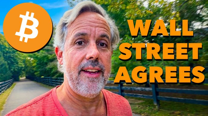 A middle-aged man with gray hair and a beard stands on a tree-lined path, with a Bitcoin logo in the top left corner and bold yellow text reading "WALL STREET AGREES" on the right side. The image visually reinforces the post's message about Wall Street institutions joining the bullish sentiment on Bitcoin during "Uptober."