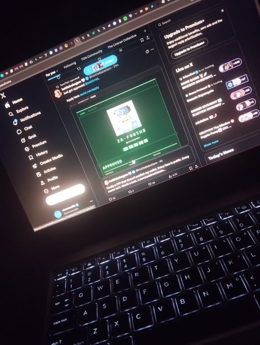 A laptop screen in a dark room displays a social media feed on X with a post showing a 'ZA_FOOSHA' image marked 'APPROVED'.