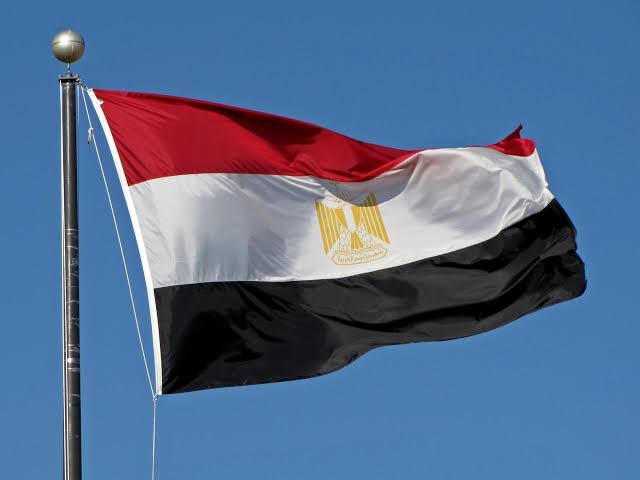 The Egyptian flag flies against a blue sky, displaying its red, white, and black horizontal stripes with the golden Eagle of Saladin emblem at the center, celebrating an achievement marked as "الثاااااااااني" (the second).