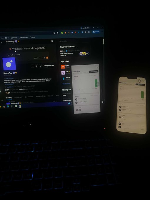 A dark room with a laptop and smartphone displaying MoonPay in Vietnamese, including the question 'What can we tackle together?'.