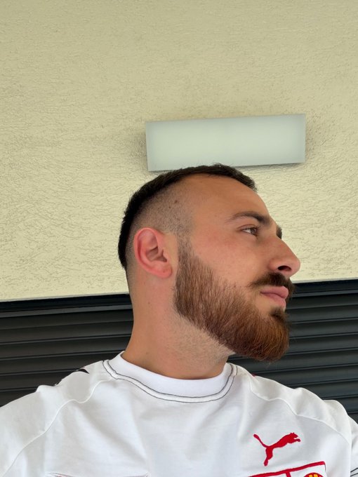 A man shown in side profile with a fresh buzzcut and well-groomed reddish beard, wearing a white Puma shirt with the red logo and "P" text visible. The casual selfie complements the "Gm friends" greeting, giving a morning-style look showcasing his new haircut.