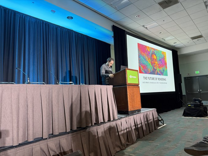 A speaker stands at a podium on stage presenting at SIGGRAPH, with the slide behind him displaying "THE FUTURE OF RENDERING" and the colorful title graphic. The audience view shows an empty front row in front of the stage where Jules Urbach is delivering his talk.