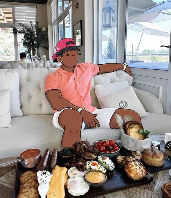 A cartoon character overlay of a man in a pink shirt and cap lounges on a white couch behind a lavish brunch spread of eggs, sausages, pastries, and tomatoes.
