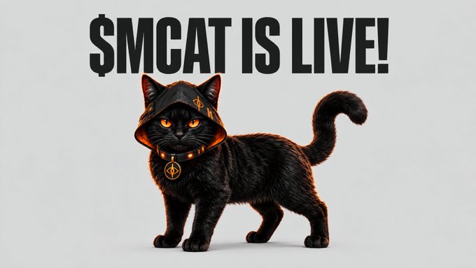 A promotional image featuring a black cat wearing a hooded outfit with an orange cryptocurrency-style collar, accompanied by bold text reading "$MCAT IS LIVE!".