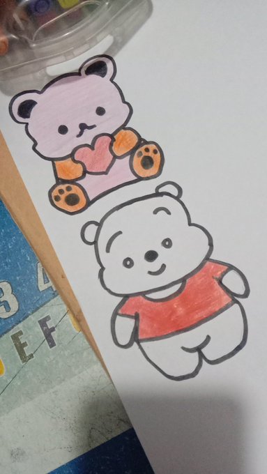 Hand-drawn cartoon stickers featuring a pink bear with a heart and a white bear in an orange shirt, sketched on white paper next to colored markers.
