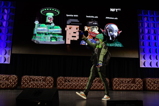 A person wearing a CryptoPunk mask stands on stage in front of a large screen displaying NFT-related content, including references to "Spottie WiFi," "betaAlt.eth," "JIRtoken.eth," and "NFT STR." The image visually supports the post's reflection on embracing a CryptoPunk identity as more than just a digital avatar, capturing a moment of pride while engaging with the NFT community on a Monday.