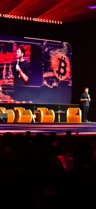 The image shows a man standing behind a podium, giving a speech or presentation. The audience appears engaged and attentive as they listen to him. There are several chairs arranged around the stage, indicating that this event may be taking place at an auditorium or similar venue. The caption "What a great presentation and speech @jackmallers at @BTCPrague Absolut wonderful." suggests that the man's speech is well-received by the audience, and they appreciate his content.