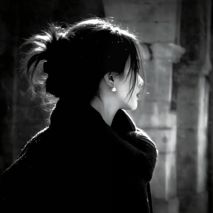 The image features a woman with long hair wearing a black coat, standing against an old stone wall or column. The photo has been edited to be in black and white, giving it a vintage appearance. The caption of the image reads "Good night Fam One big hurdle in Web3 is getting users to understand the tech before they can use it." This statement seems to be related to the woman's presence in the scene, as she appears to be standing against an old stone wall or column and possibly waiting for someone.