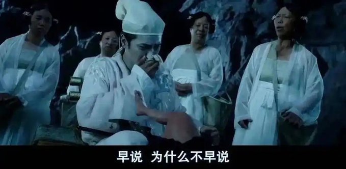 A man in white traditional Chinese robes wipes his face with a cloth while surrounded by women in similar attire, with Chinese subtitles reading "早说 为什么不早说" ("Why didn't you say so earlier"). The image humorously references the scandal surrounding Gate CEO's delayed response to the alleged insider theft, depicting him as the central tearful figure caught amid the unfolding controversy.