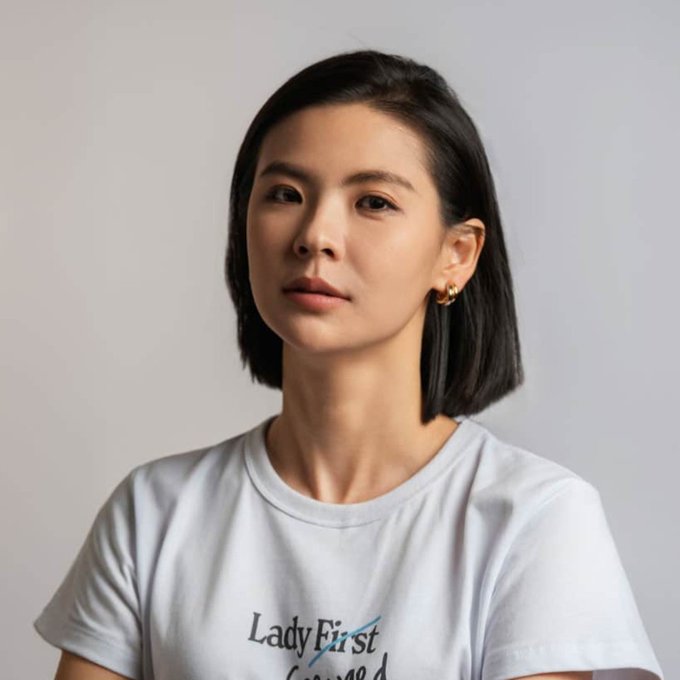 A portrait of Bitget CEO Gracy Chen, wearing a white "Lady First" t-shirt and gold hoop earrings, in a neutral studio setting. The image relates to the post as it features the cryptocurrency executive who described 2026 as a volatile "monkey market."