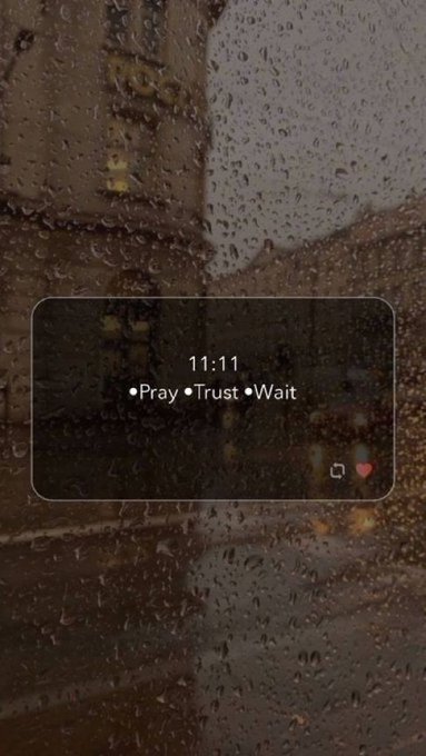 A rainy window with a digital overlay displaying the time '11:11' and the text '•Pray•Trust•Wait'.