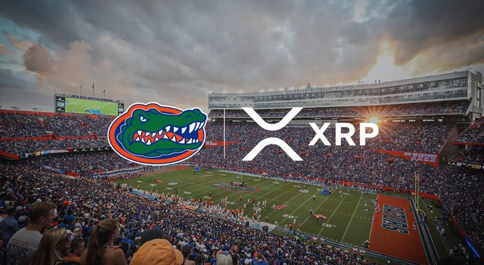 The image shows a packed football stadium, identified as the University of Florida's Ben Hill Griffin Stadium (also known as "The Swamp") by the orange and blue color scheme and the iconic Florida Gators alligator logo overlaid on the left side. Next to the Gators logo is the XRP cryptocurrency logo, visually combining the university branding with the digital asset to tie in with the post's "FLORIDA XRP" caption.