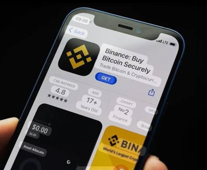 A hand holds a smartphone displaying the Binance cryptocurrency app's download page on the App Store, showing a 4.8-star rating from 7.8K reviews and a "No. 2 in Finance" chart position. The image supports the post's theme by visually presenting Binance as an all-in-one crypto solution that simplifies financial management compared to juggling multiple traditional banking and investment apps.
