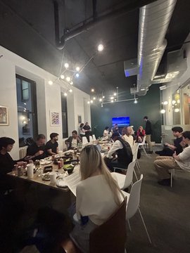 A group of attendees gathered around a long table at a Blockchain Tuesday event in NYC, engaged in discussion during an AI on-chain roundtable that ran well past the scheduled end time.