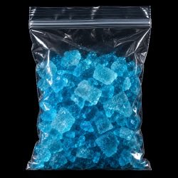 A clear plastic ziplock bag filled with bright blue crystalline chunks, likely rock candy or sugar crystals, photographed against a black background.