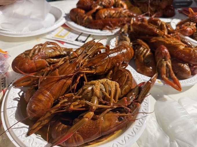 A pile of cooked crawfish served on paper plates at what appears to be a crawfish boil or seafood feast.