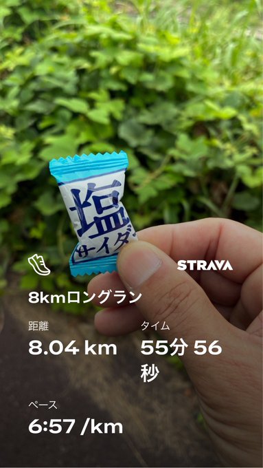 A Strava activity summary titled '8kmロングラン' (8km Long Run) showing 8.04 km distance, 55 minutes 56 seconds time, and a 6:57/km pace, with a hand holding a Japanese salt candy (塩) packet against a green foliage background.