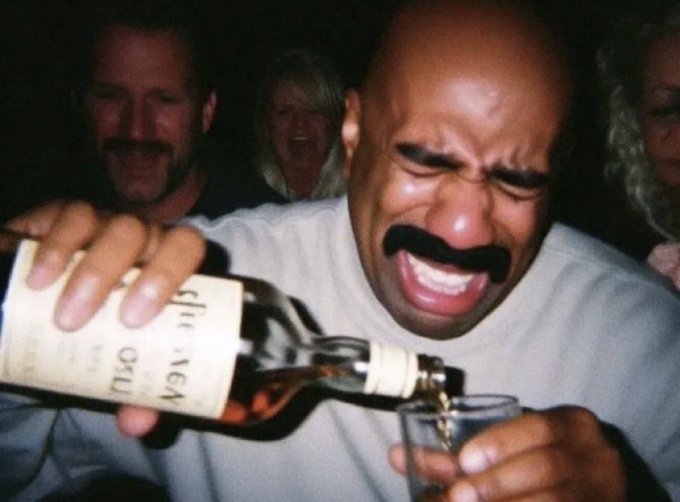 A man with a mustache reacts with a pained expression as he pours liquor from a bottle into a glass, with other people visible in the background.