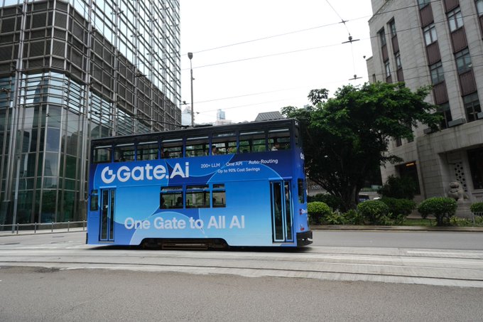 A blue double-decker tram advertising 'Gate.ai' with the slogan 'One Gate to All AI' traveling on city tracks between urban buildings.