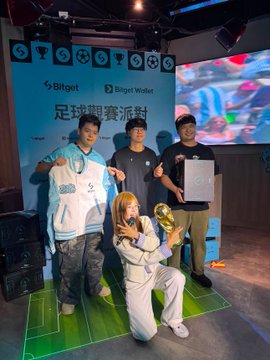 Three people pose together at the Bitget football viewing party, with one holding a signed Manchester City jersey and a Golden Trophy Ball while the Bitget and Bitget Wallet logos appear on the backdrop screen, capturing the celebratory aftermath of the 1-0 final match result.