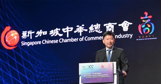 A man in a dark suit speaks at a podium during the SMEICC 2026 conference, with the backdrop displaying "新加坡中華總商會 Singapore Chinese Chamber of Commerce and Industry" and a sign on the podium reading "SMEICC 2026 BEYOND PARTNERSHIPS FUELED BY SINGAPORE'S COMPASS," aligning with the launch of the Agentic Decentralized Finance Forum held on 6 August.