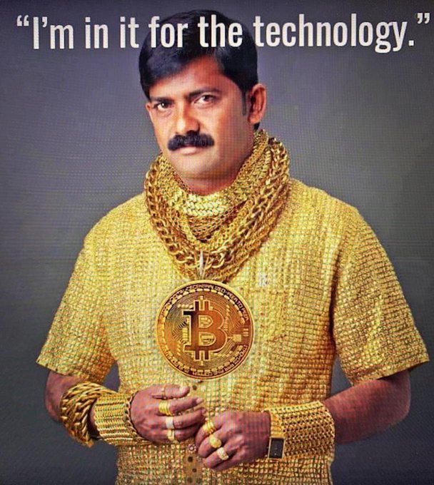 A man dressed in gold clothing adorned with gold chains and a large Bitcoin medallion says, 'I'm in it for the technology.'
