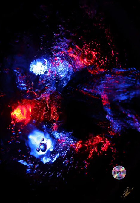 A vibrant abstract artwork featuring swirling blues, reds, and bright white highlights against a dark background, displaying a circular "NFT NYC" badge in the bottom right corner alongside an artist's signature. The image celebrates the creator's third consecutive year being featured at NFT.NYC 2026, with the badge visually confirming their participation in the prestigious digital art event in New York and Times Square.