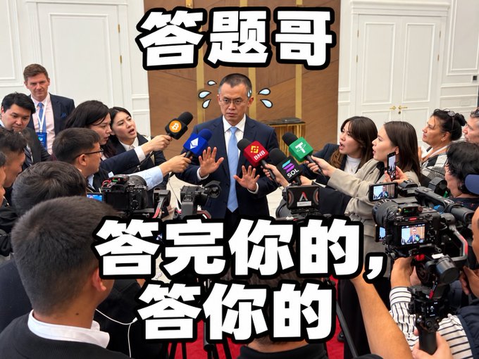 A photo of a man in a suit surrounded by reporters holding multiple microphones and cameras, with Chinese meme text overlaid reading '答题哥' at the top and '答完你的，答你的' at the bottom.