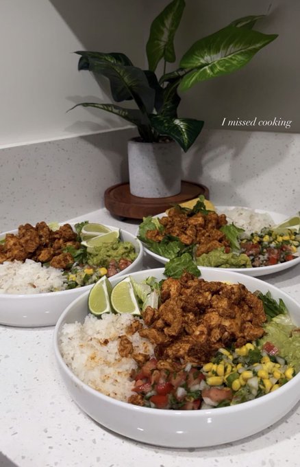 The image features three bowls of food, each containing rice, chicken, lettuce, and other ingredients such as corn and guacamole. The bowls are placed on a white countertop or table. A potted plant can be seen behind one of the bowls, adding a touch of greenery to the scene. The post in the image is about a week ago, discussing how people have been spending their time during this period.