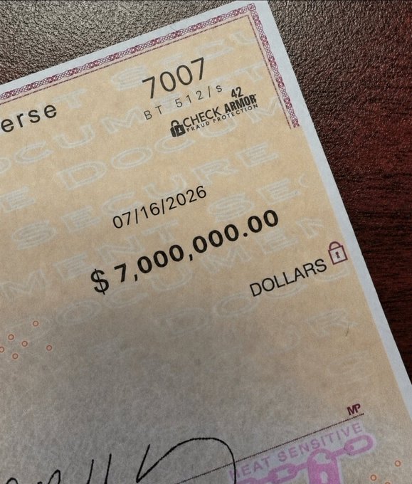 A close-up of a counterfeit-looking novelty check made out for "$7,000,000.00" dated 07/16/2026, with "DOLLARS" and the number "7007" visible—evoking the spiritual prosperity theme of the post suggesting that "miracle money" is on its way to the viewer.