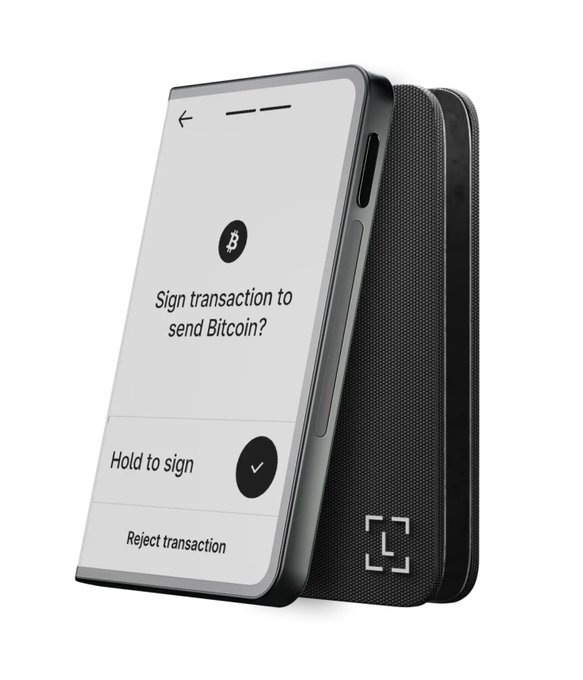 A product image of a black hardware cryptocurrency wallet with its phone app displaying "Sign transaction to send Bitcoin?" with options to "Hold to sign" or "Reject transaction."
